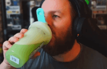 a man wearing headphones is drinking a green smoothie