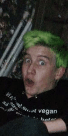 a young boy with green hair is making a funny face .