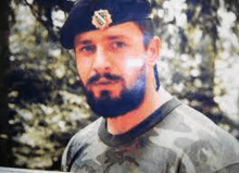 a man with a beard wearing a beret and a camouflage shirt is looking at the camera .