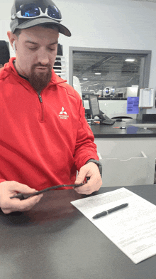 a man in a red mitsubishi shirt is looking at a tablet