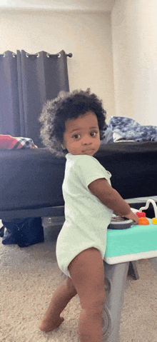 a baby in a diaper is standing next to a toy in a living room