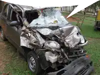 a damaged car with a broken windshield sits in a grassy field