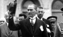 a black and white photo of a man in a suit and tie waving his hat