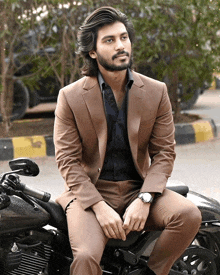 a man in a brown suit sits on a black motorcycle