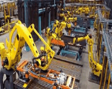 a factory filled with lots of yellow robots working on a piece of metal .