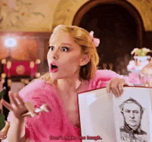 a woman in a pink dress holds a picture of a man