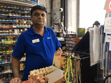 a man in a blue shirt is holding a box of raw