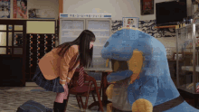 a girl in a school uniform looks at a stuffed animal in front of a vending machine that says ' coca cola '