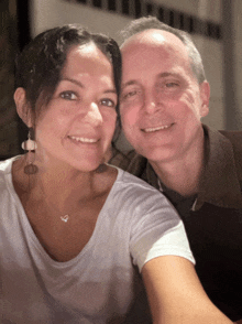 a man and woman are posing for a picture and the woman has a heart necklace