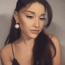 a close up of a woman wearing a black top and earrings .