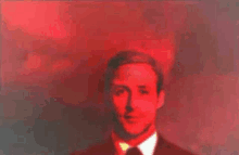 a man in a suit and tie is standing in a red room .