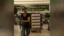 a man in a cowboy hat stands in front of a sign that says thank you for shopping at blaine 's