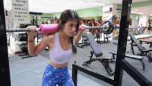 a woman squatting in a gym with a sign on the wall that says not only changes your body it changes your mind