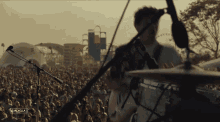 a man playing a guitar in front of a crowd at a music festival with a sign that says " coachella "