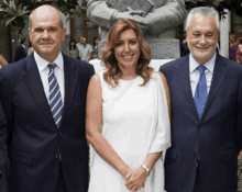 two men and a woman are posing for a picture in front of a statue