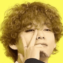 a close up of a person with curly hair making a peace sign .