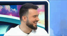 a man with a beard is smiling in front of a monitor