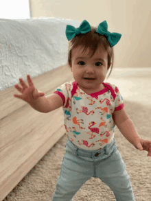 a baby girl wearing a flamingo onesie and jeans