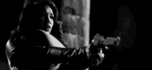 a black and white photo of a woman holding a gun in her hand .