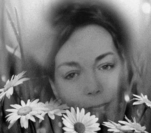 a black and white photo of a woman with daisies in the foreground