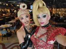 two drag queens are posing for a photo in a restaurant