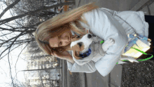 a woman in a white jacket is holding a small brown and white dog