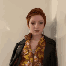 a young woman with red hair is wearing a floral shirt and a leather jacket