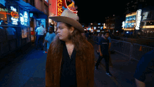 a man in a cowboy hat stands in front of a sign that says ' coca cola ' on it