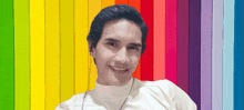 a man wearing earbuds smiles in front of a colorful background