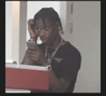 a man is looking at his cell phone in front of a red cooler .