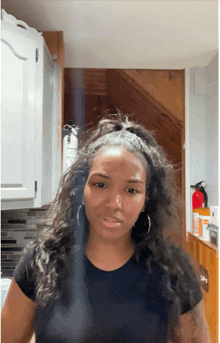 a woman in a black shirt is standing in a kitchen