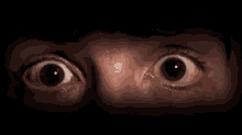 a close up of a person 's eyes with a surprised look on their face in the dark .