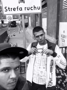 two men standing in front of a street sign that says strefa ruchu