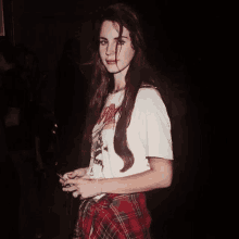 lana del rey is wearing a white t-shirt and plaid skirt .