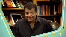 a man in a black shirt is smiling in front of a bookshelf that has a book titled light on it