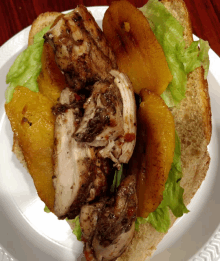 a close up of a chicken sandwich with lettuce and pineapple on a plate