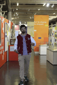 a man in a varsity jacket is walking in a museum