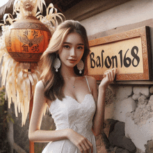 a woman in a white dress is standing in front of a sign that says balon168