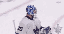 two hockey players are standing next to each other on the ice and one of them is wearing a helmet .