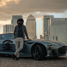 a man wearing a mask leans against a silver sports car with a sticker that says moose man