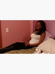 a woman is laying on a bed with a purple wall behind her