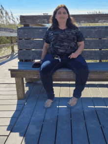 a woman sits on a wooden bench on a boardwalk