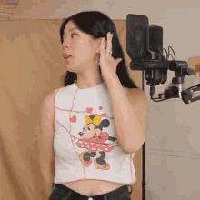 a woman wearing a minnie mouse crop top is standing in front of a microphone