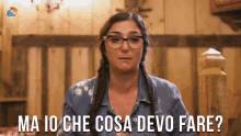 a woman wearing glasses and a denim shirt has the words ma io che cosa devo fare below her