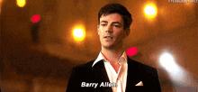 a man in a suit and white shirt is standing in front of a crowd and talking to barry allen .