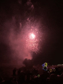 a crowd of people watching fireworks with glow in the dark sunglasses in the foreground