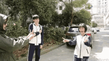 a boy and a girl are standing next to each other on a street with a car in the background