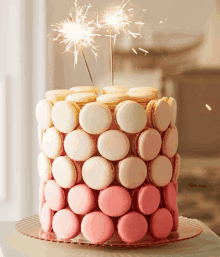 a pink and white cake with sparklers on top of it