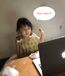 a little girl sitting in front of a laptop with a speech bubble that says chin chao !!!