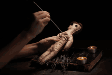 a person is making a voodoo doll with a needle .